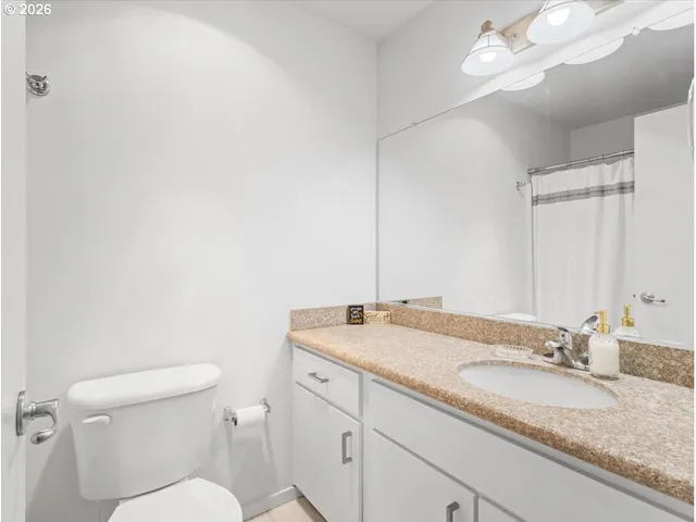 a bathroom with a granite countertop toilet sink and mirror