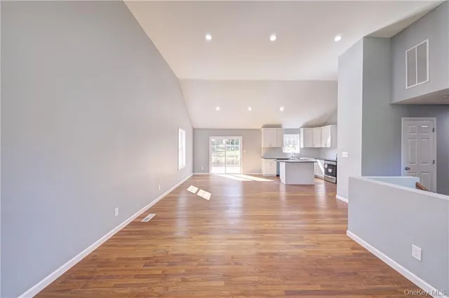 an empty room with wooden floor ceiling fan and windows
