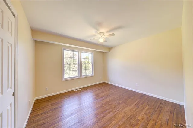 a view of a hallway with wooden floor and a ceiling fan