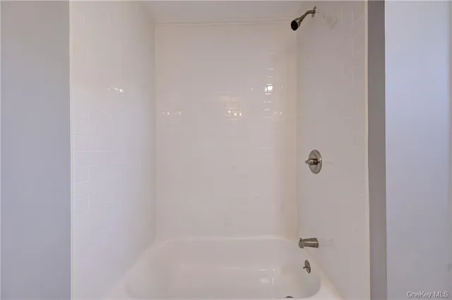 a view of an empty room with wooden floor and a ceiling fan