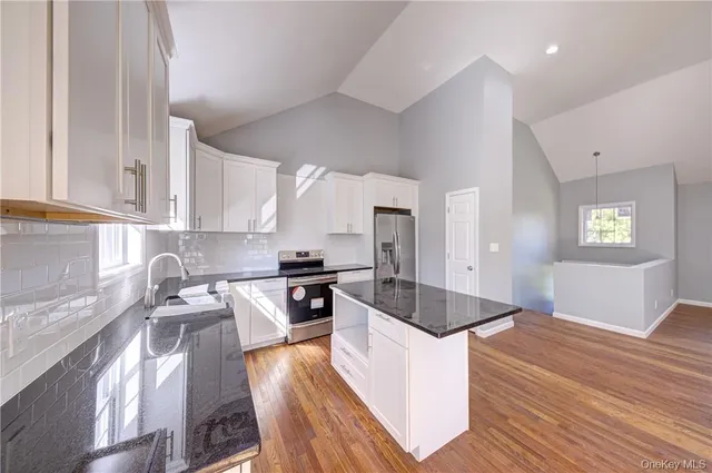 a kitchen with granite countertop a stove sink and cabinets