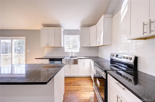 a view of an empty room with wooden floor and window