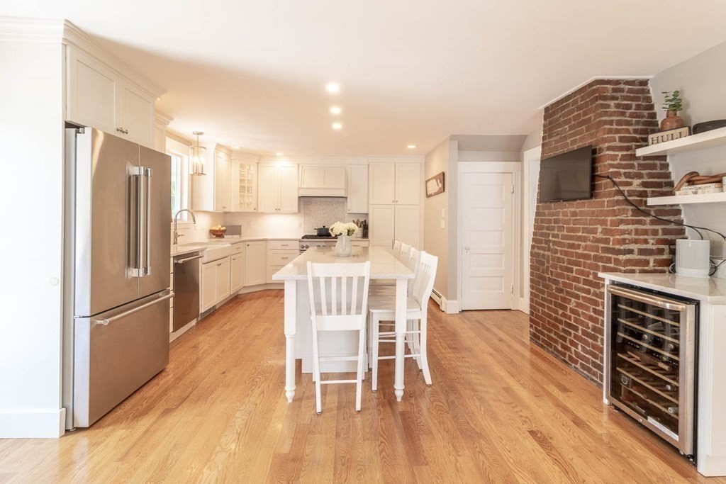 203 Samoset Avenue Hull, MA 02045 - Photo 13 of 39 a kitchen with stainless steel appliances a refrigerator a stove top oven and a dining table with wooden floor