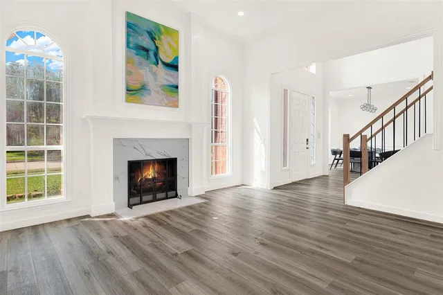 a view of an empty room with wooden floor fireplace and a window