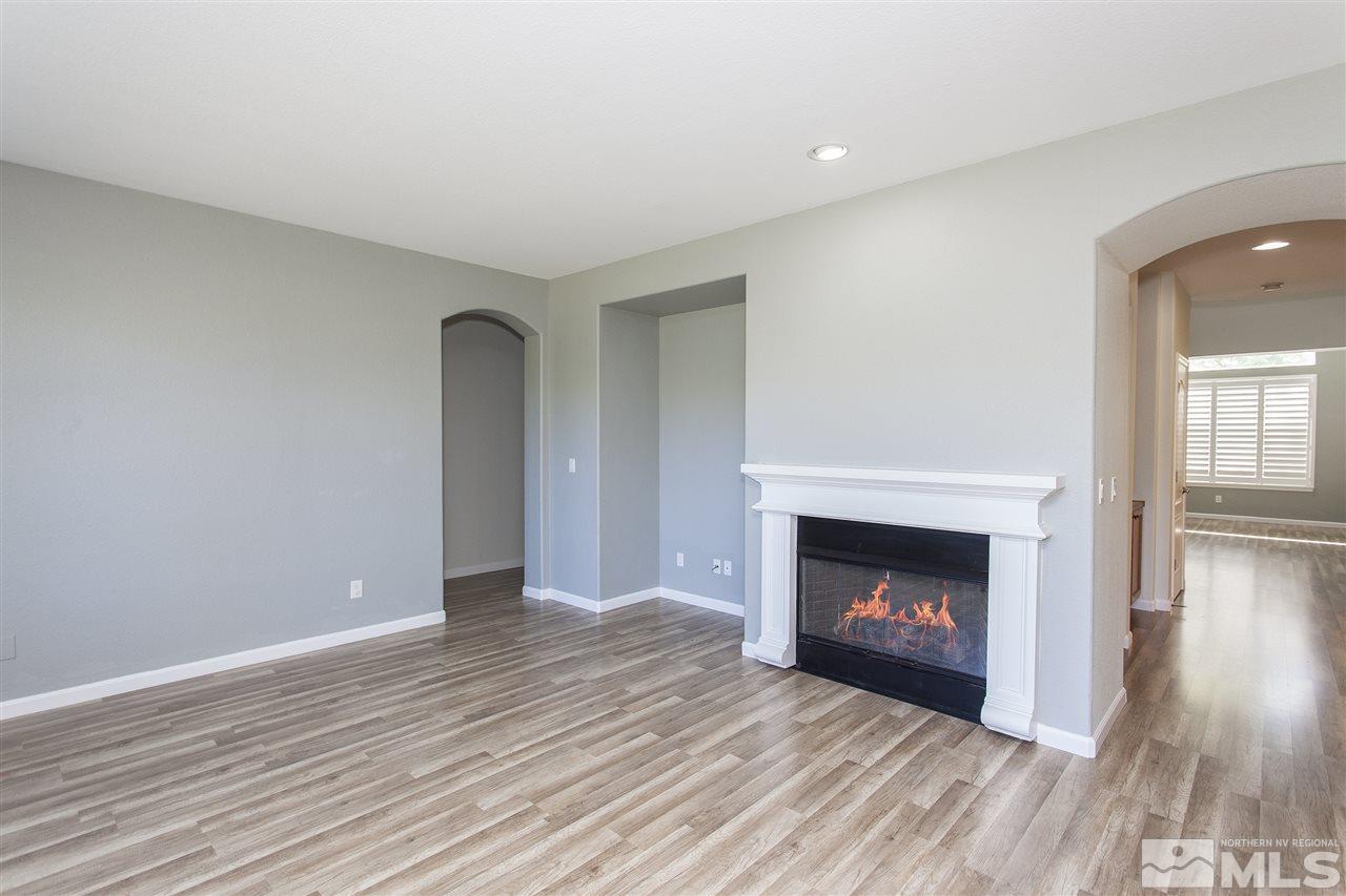 581 Alydar Court Reno, NV 89521 - Photo 3 of 22 a view of an empty room with wooden floor fireplace and a window