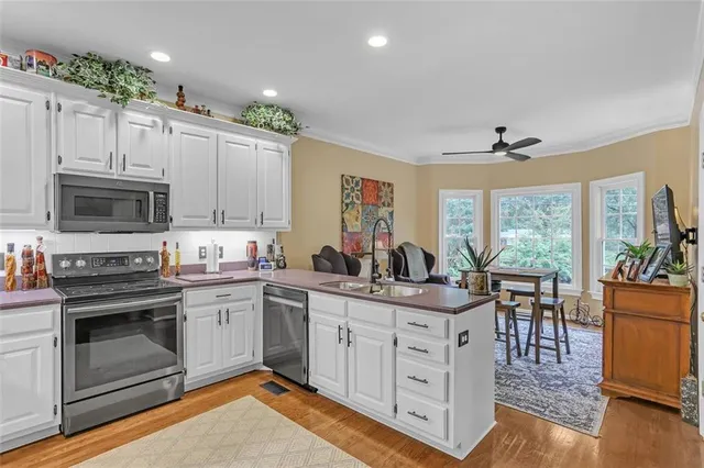 a kitchen with white cabinets stainless steel appliances and wooden floor