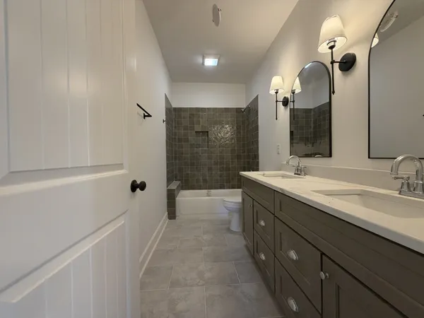 a spacious bathroom with a double vanity sink a mirror and a bathtub