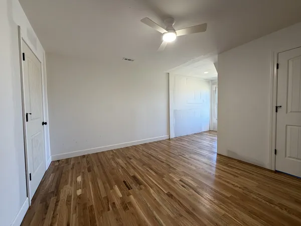a view of a room with wooden floor and a ceiling fan
