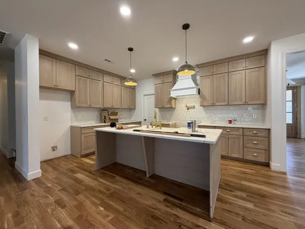 a kitchen with kitchen island granite countertop a sink cabinets and wooden floor