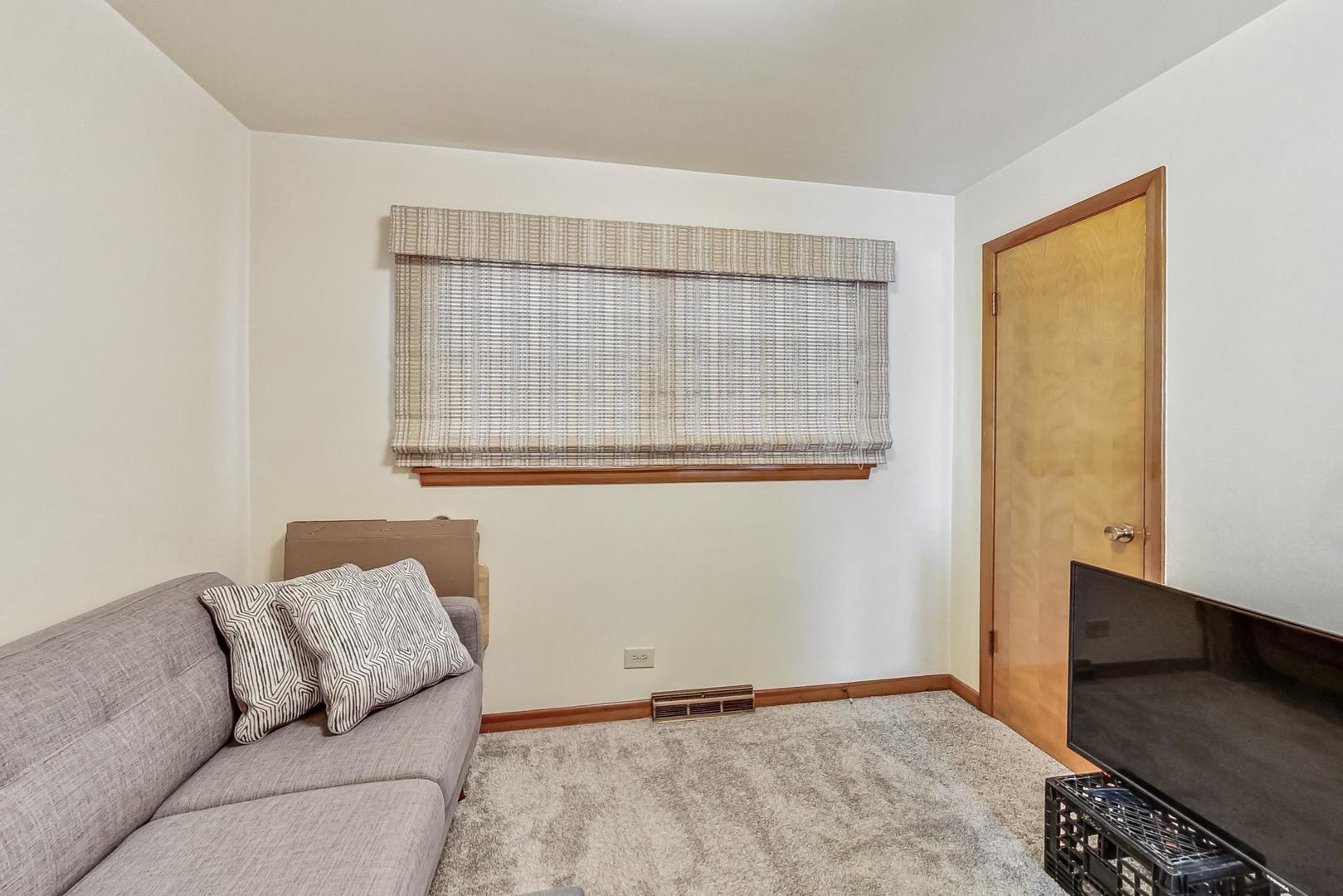 6241 South Rutherford Avenue Chicago, IL 60638 - Photo 13 of 39 a living room with a couch and a dresser next to a window