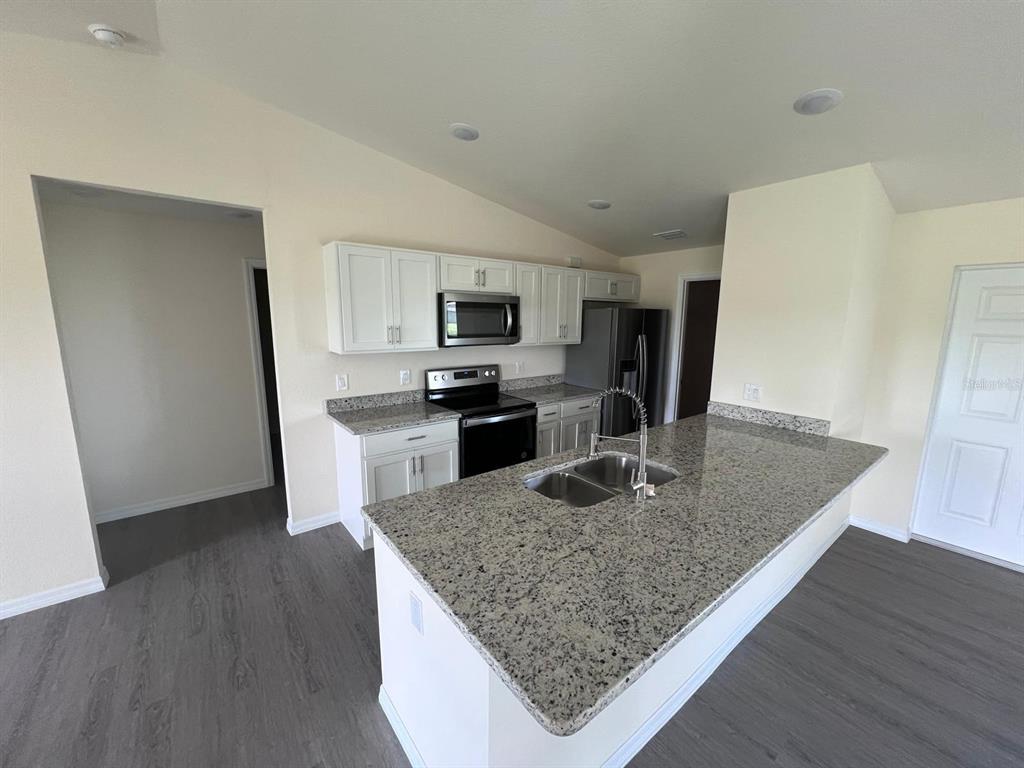 13731 Southwest 89 Circle Ocala, FL 34473 - Photo 4 of 34 a kitchen with kitchen island a counter top space appliances and cabinets