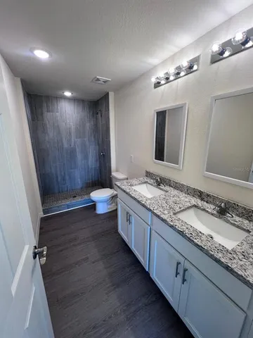 a bathroom with a granite countertop sink a large mirror and a shower