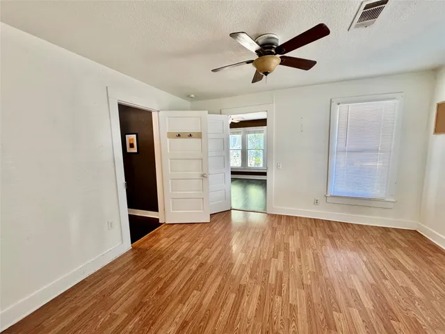 a view of empty room with wooden floor and ceiling fan