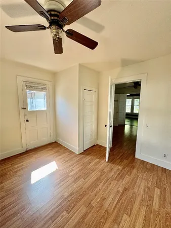 an empty room with wooden floor chandelier fan and windows