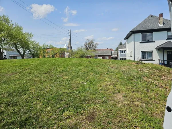 a view of a big house with a big yard and large trees