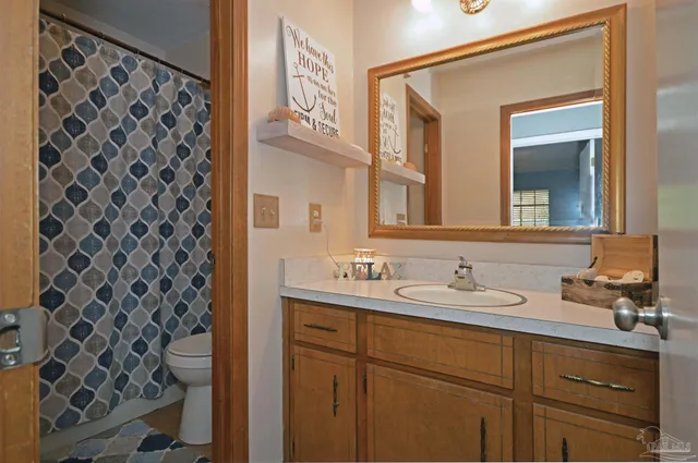 a bathroom with a granite countertop sink toilet and mirror