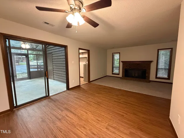 a view of empty room with wooden floor and fan