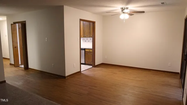 an empty room with wooden floor chandelier fan and closet area