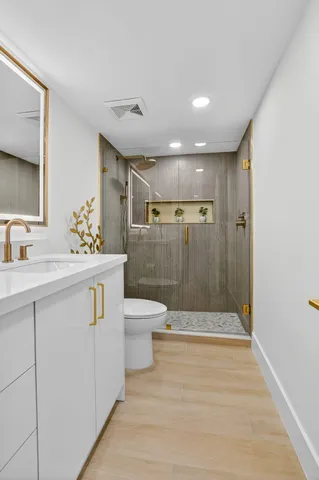 a bathroom with a granite countertop toilet sink and mirror