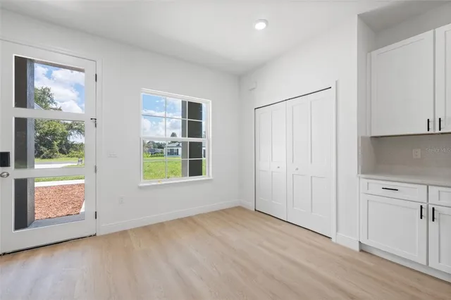 a kitchen with stainless steel appliances granite countertop a sink a stove a refrigerator white cabinets and wooden floor