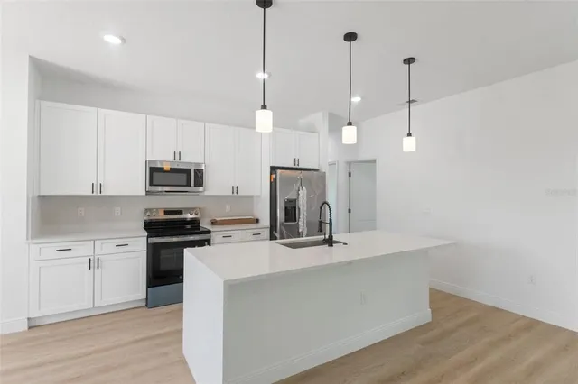 a kitchen with stainless steel appliances a refrigerator a sink a center island a stove and white cabinets