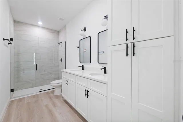a bathroom with a double vanity sink toilet mirror and shower