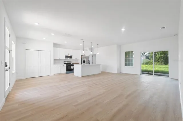 a view of a kitchen with kitchen island a sink wooden floor and a refrigerator