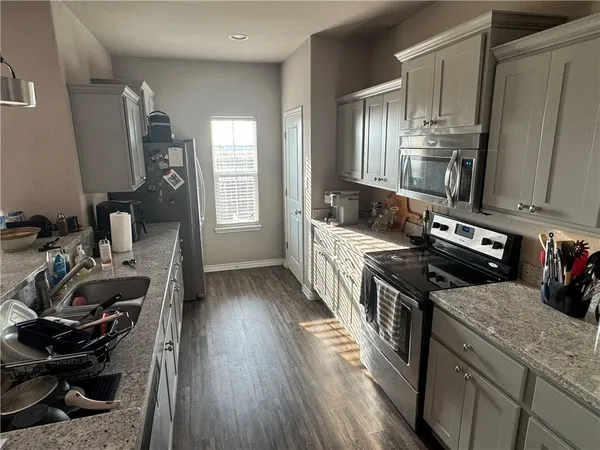a kitchen with a sink appliances wooden floor and a window