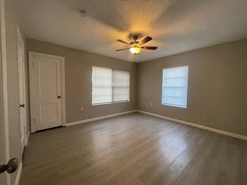 1114 East Pecan Street Angleton, TX 77515 - Photo 12 of 20 an empty room with wooden floor chandelier fan and windows