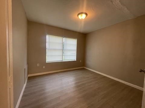 1114 East Pecan Street Angleton, TX 77515 - Photo 13 of 20 an empty room with wooden floor and windows