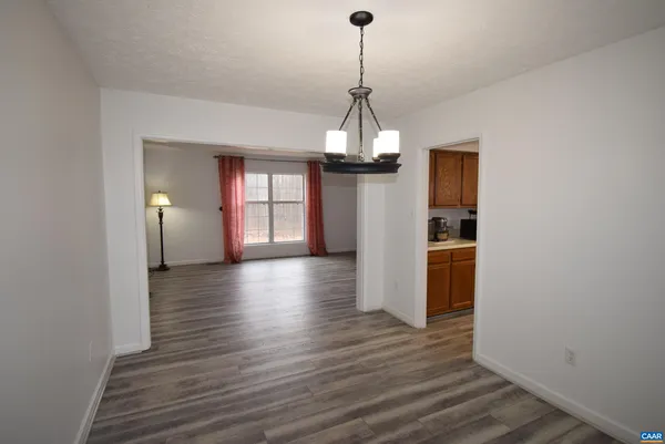 a view of a hallway with wooden floor and a chandelier