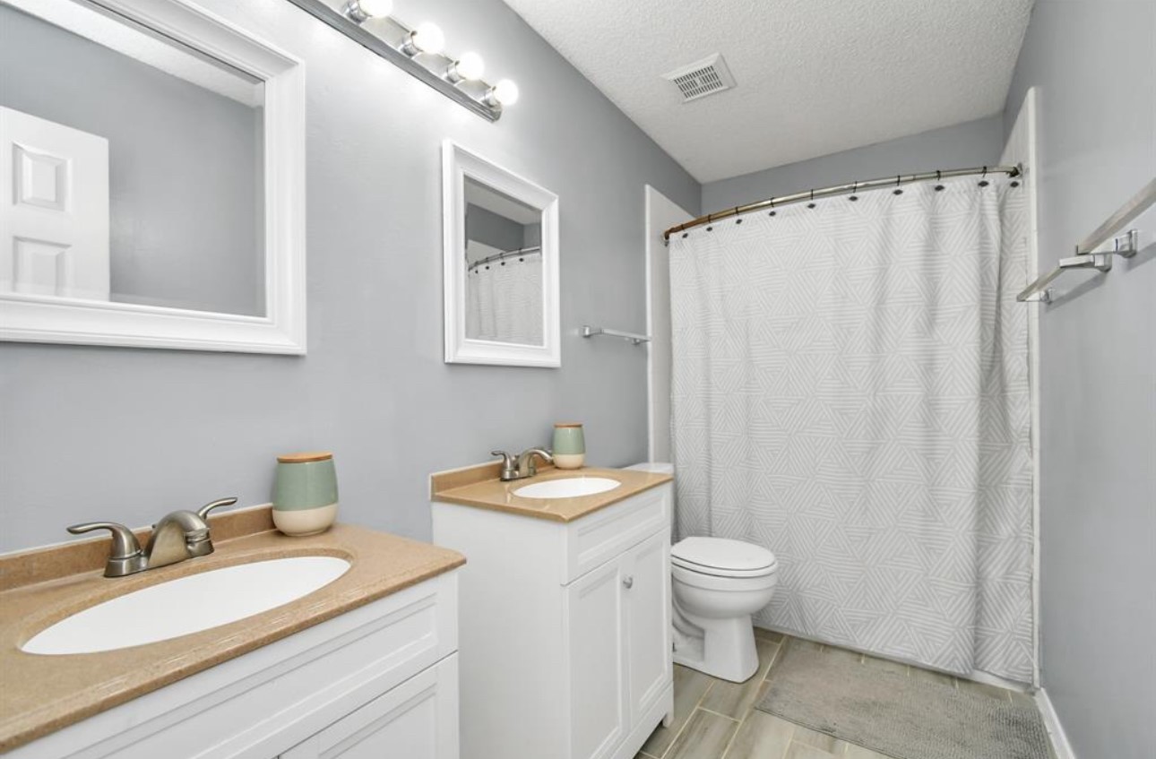 10234 Tablerock Drive Houston, TX 77064 - Photo 18 of 20 a bathroom with a granite countertop sink toilet a mirror and shower curtain