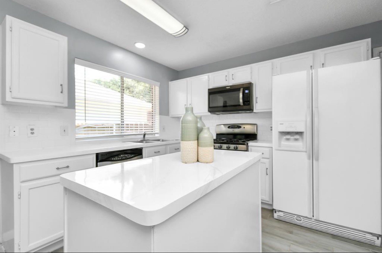 10234 Tablerock Drive Houston, TX 77064 - Photo 7 of 20 a kitchen with kitchen island a white counter top space stainless steel appliances a window and a view of living room