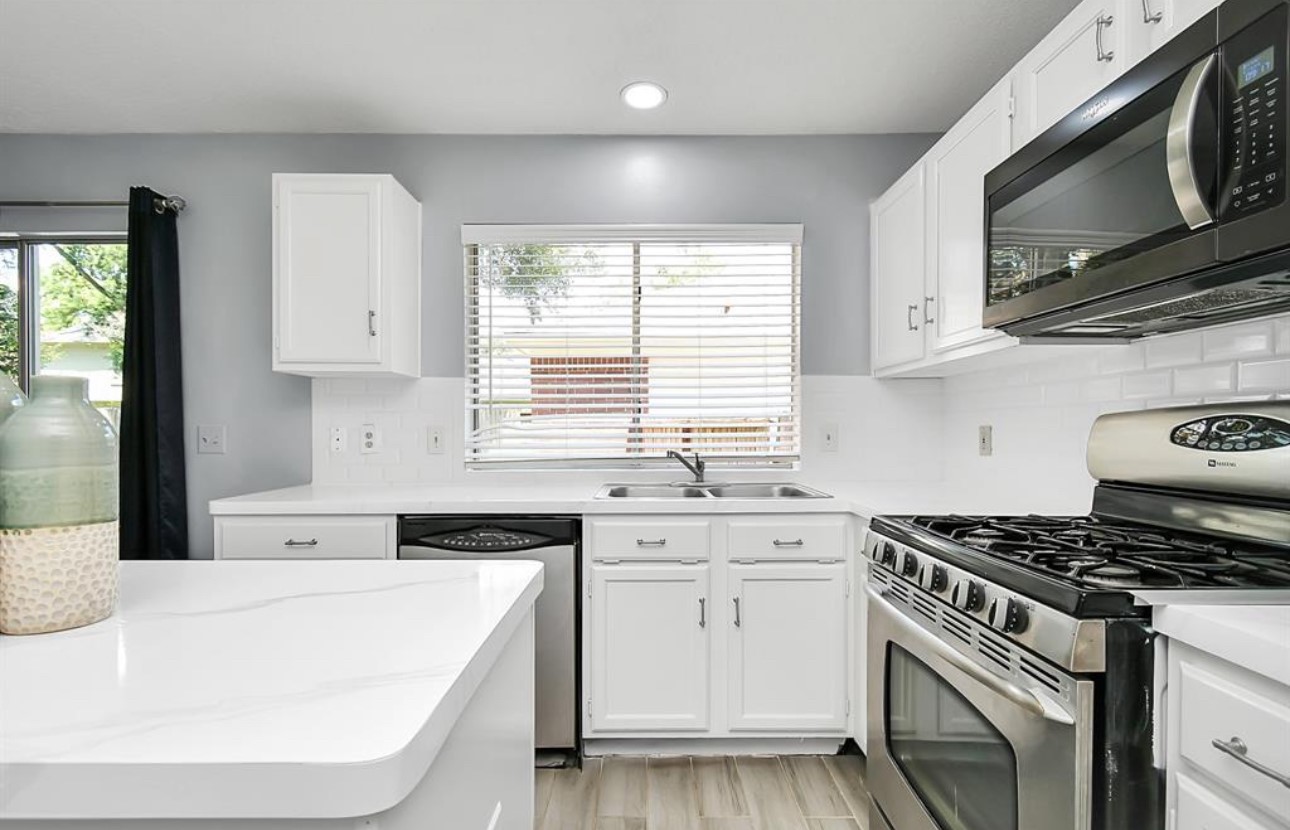 10234 Tablerock Drive Houston, TX 77064 - Photo 8 of 20 a kitchen with stainless steel appliances white cabinets a sink a stove a microwave and wooden floors