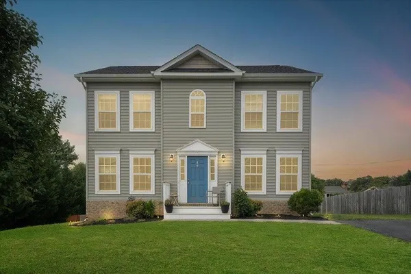 a front view of a house with a yard and trees