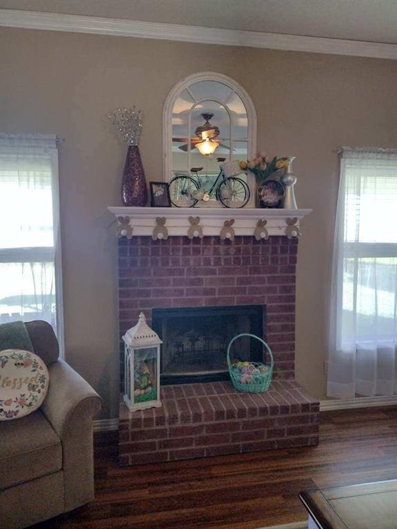 4617 Lexington Street Waco, TX 76705 - Photo 7 of 14 Living area featuring healthy amount of natural light, ornamental molding, dark wood-style flooring, and a fireplace with raised hearth