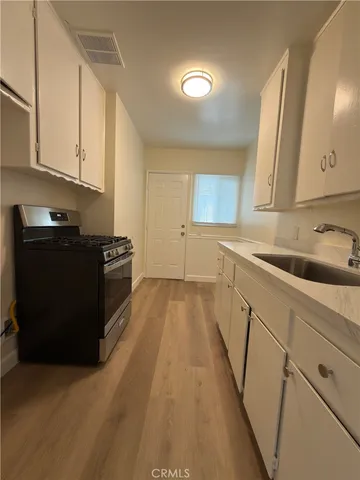 a kitchen with granite countertop a sink dishwasher stove and cabinets