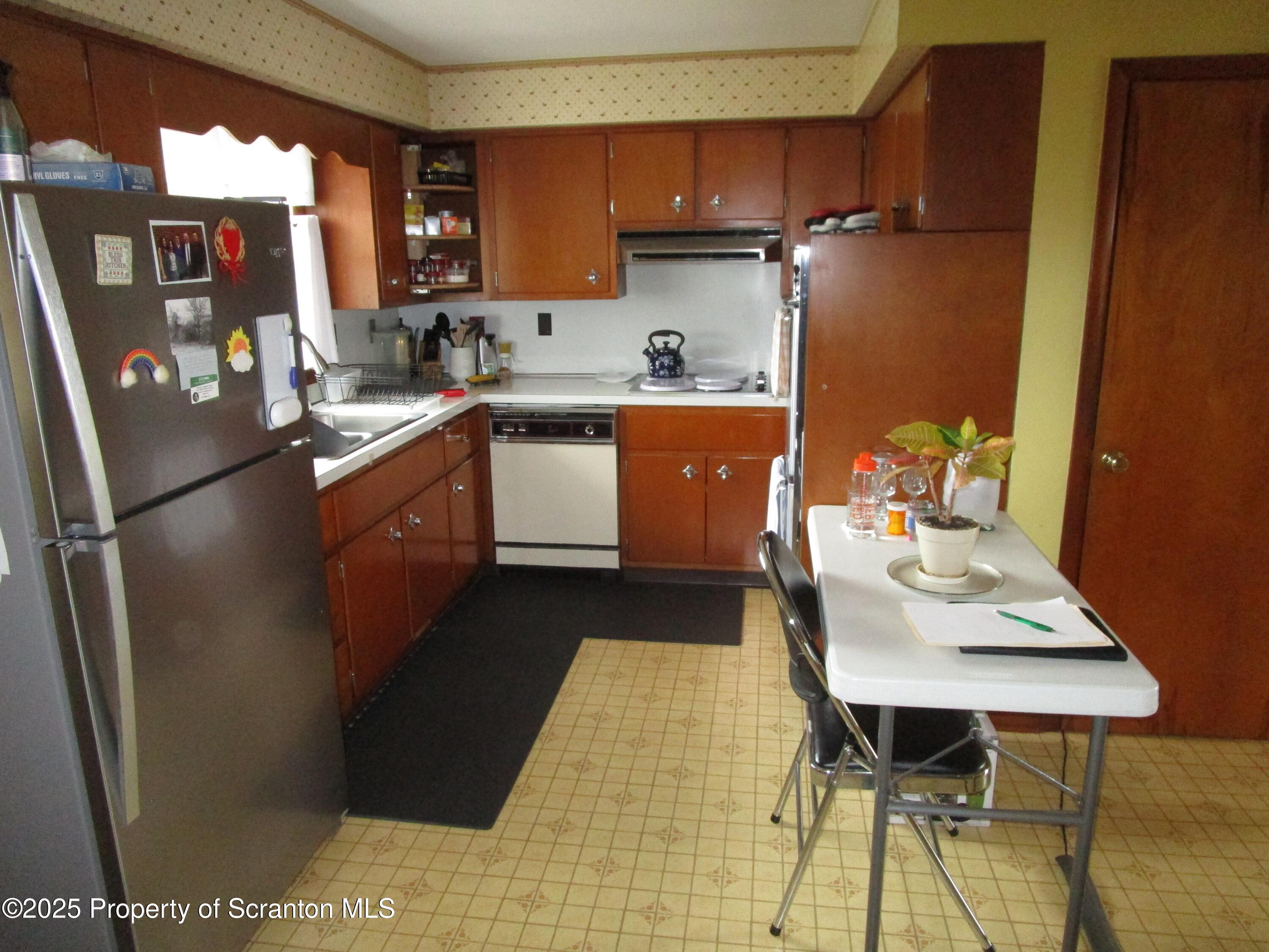 715 Moritz Street Dunmore, PA 18512 - Photo 5 of 14 a kitchen with stainless steel appliances granite countertop a refrigerator a sink dishwasher a stove a dining table and chairs with wooden floor