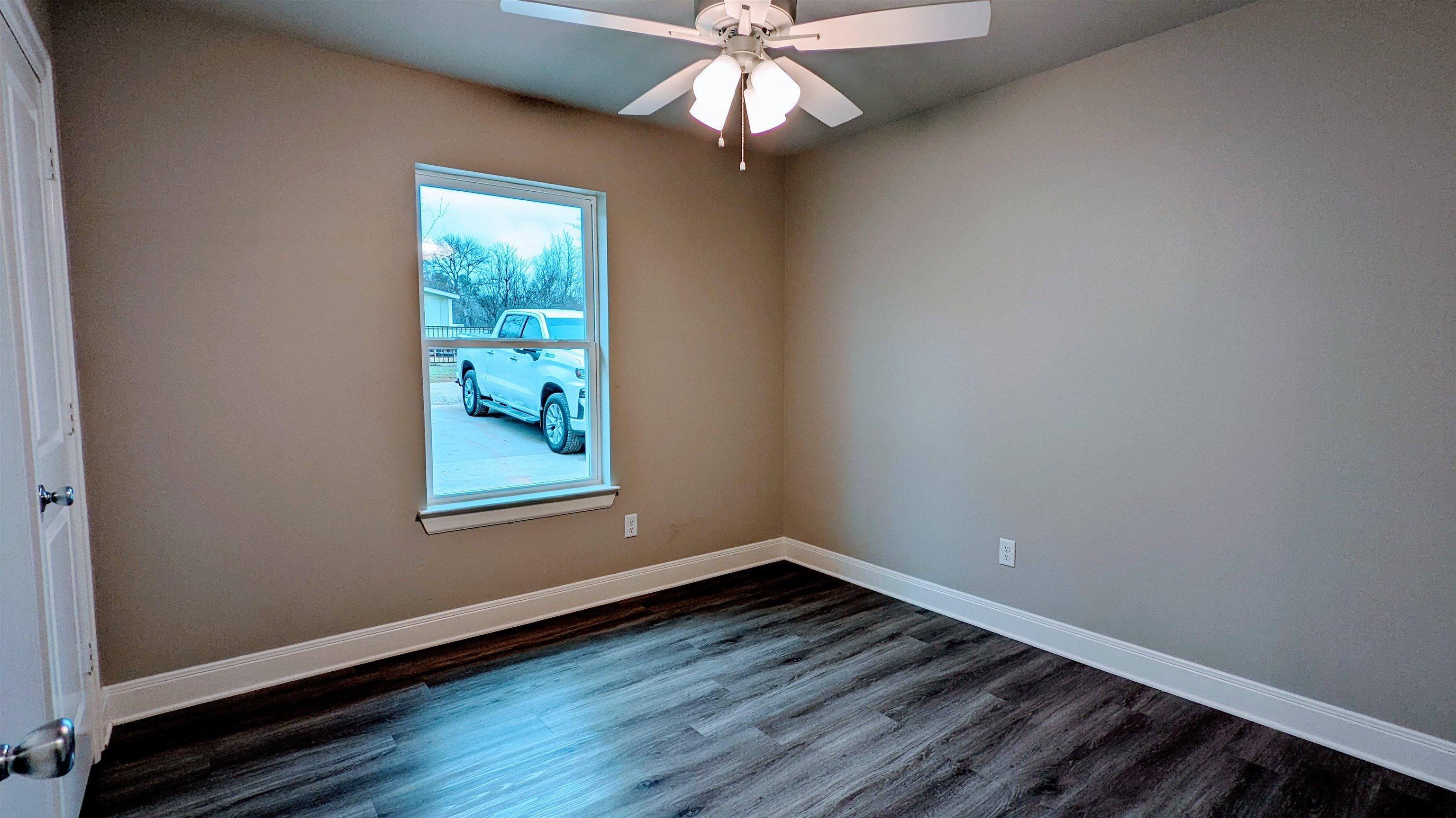 11672 Fm 2015, Unit B Tyler, TX 75708 - Photo 5 of 16 an empty room with wooden floor chandelier fan and windows