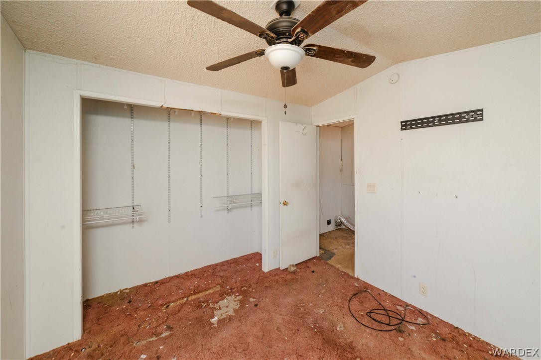 16435 South Wyatt Earp Road Yucca, AZ 86438 - Photo 11 of 57 Room featuring a ceiling fan with wood-finish blades, a wall-mounted bracket, and an open doorway