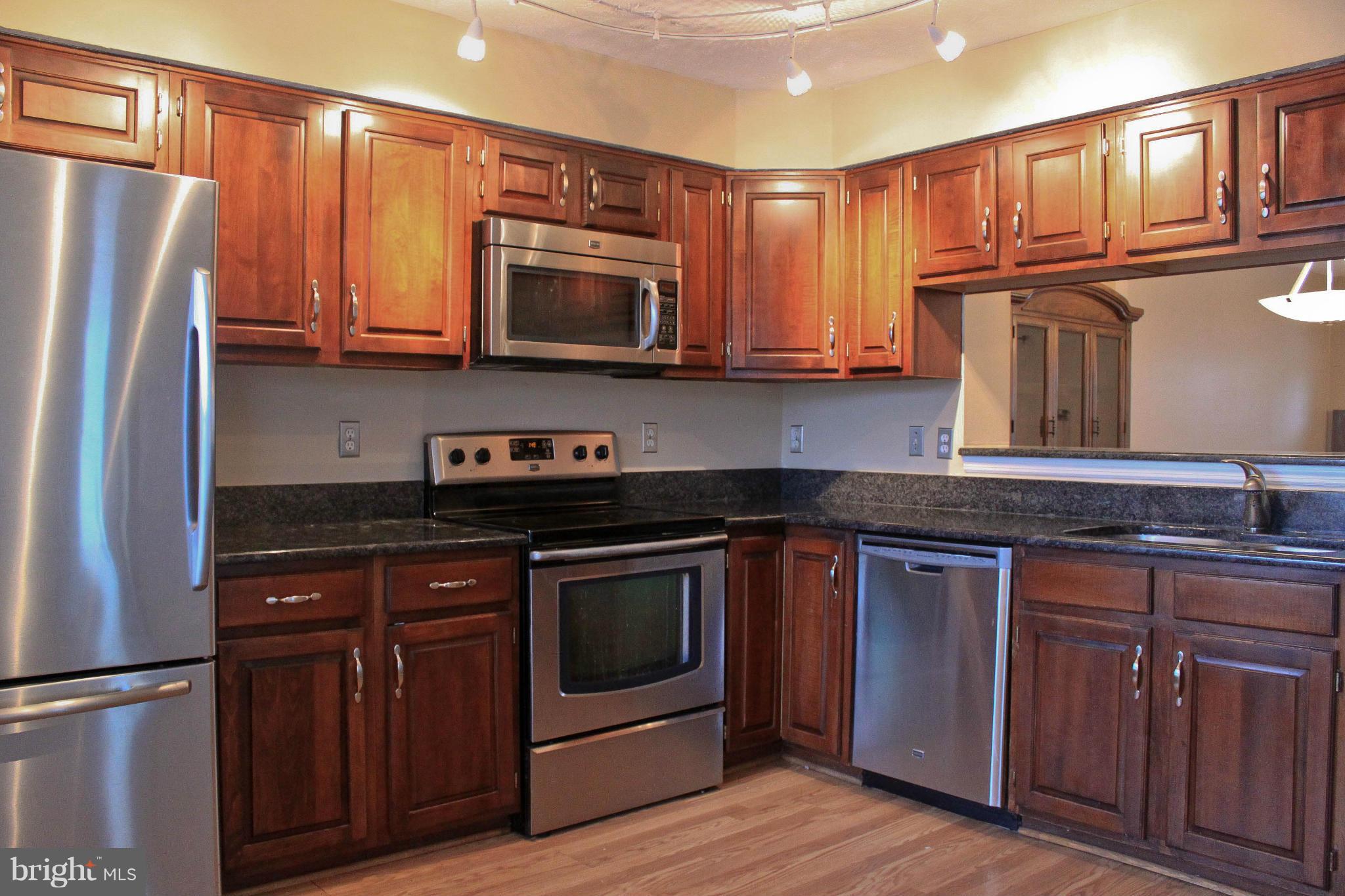 44001 Choptank Terrace Ashburn, VA 20147 - Photo 2 of 11 a kitchen with granite countertop wooden cabinets and stainless steel appliances
