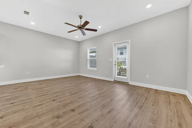 a view of an empty room with wooden floor and a window