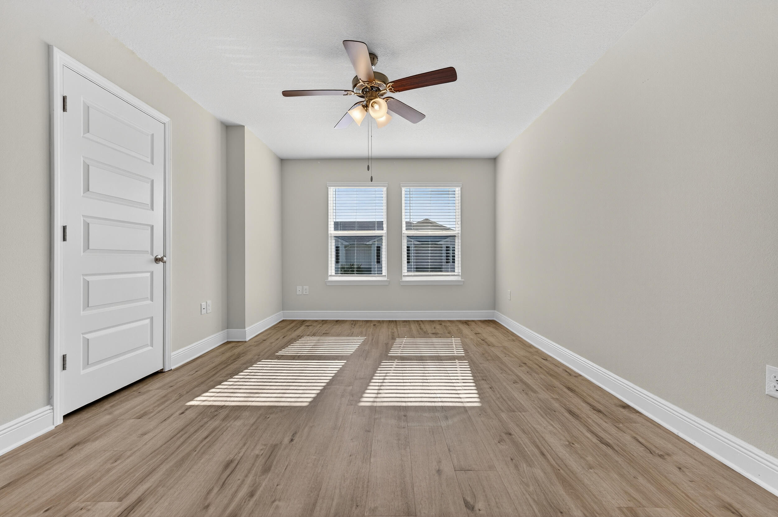15 Redbird Loop Destin, FL 32541 - Photo 22 of 42 an empty room with wooden floor chandelier fan and windows