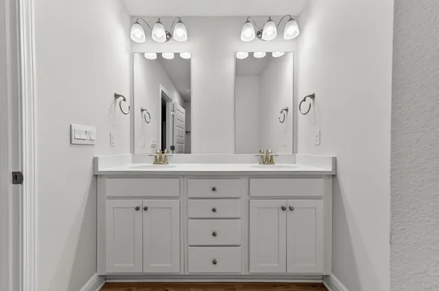 a bathroom with double vanity sinks a vanity a lamp and a mirror