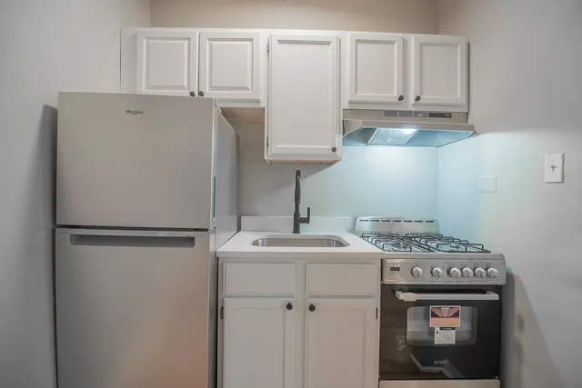 a kitchen with stainless steel appliances granite countertop a refrigerator sink and white cabinets