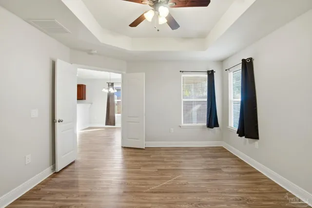 an empty room with wooden floor and windows