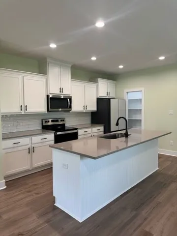 a kitchen with stainless steel appliances granite countertop a sink a stove top oven a counter space and cabinets