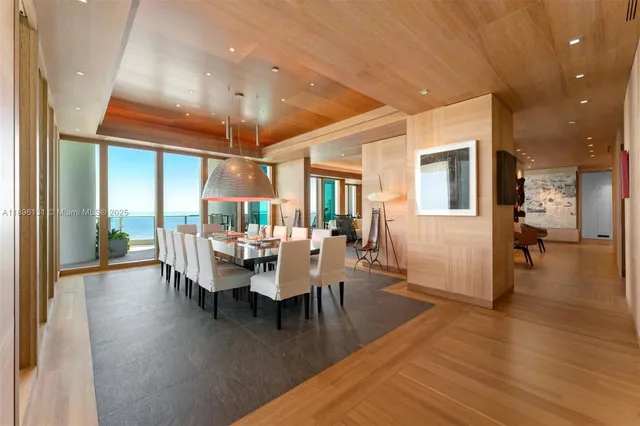 a dining room with wooden floor a chandelier a glass table and chairs