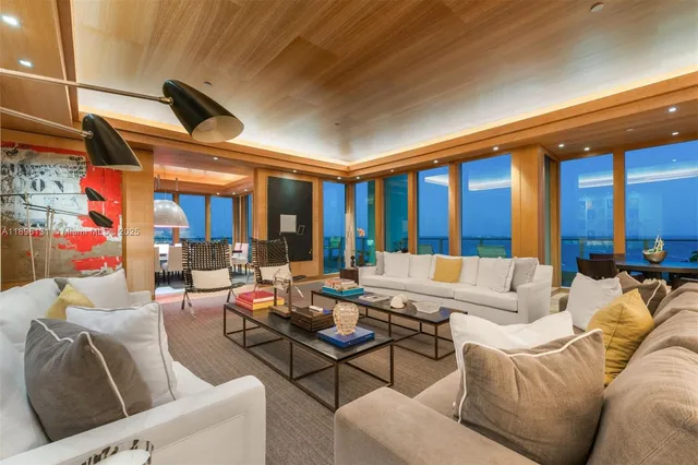 a living room with furniture kitchen view and large windows
