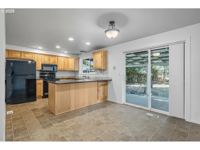 a kitchen with stainless steel appliances granite countertop a stove a sink a refrigerator white cabinets and a large window